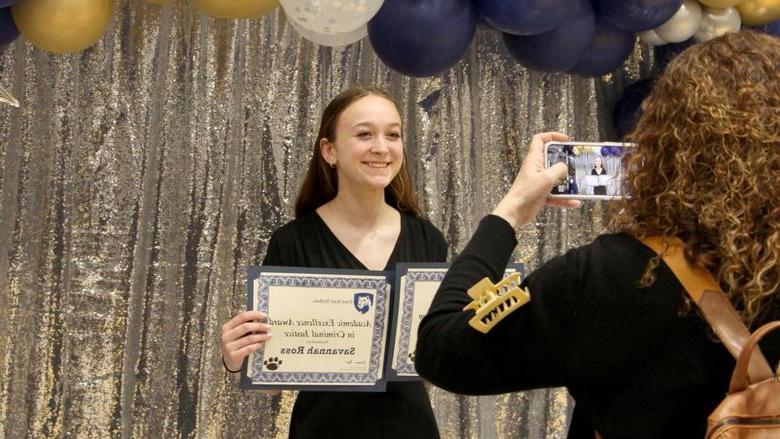 Penn State DuBois student Savannah Ross pauses with her awards for a photo, taken by a family member, at the recognition and awards banquet at the PAW Center.